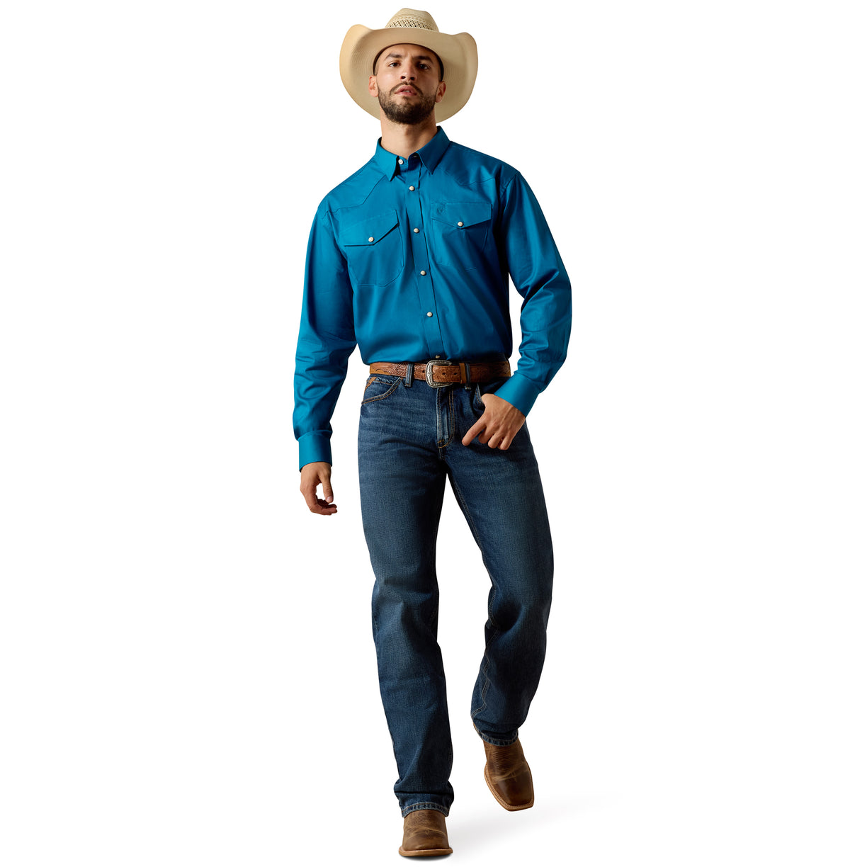 A man wearing a bright blue long-sleeve western shirt, dark blue jeans, a brown belt, and a beige cowboy hat, standing against a plain white background.