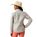 Woman wearing a patterned long-sleeve shirt and pink pants on a white background