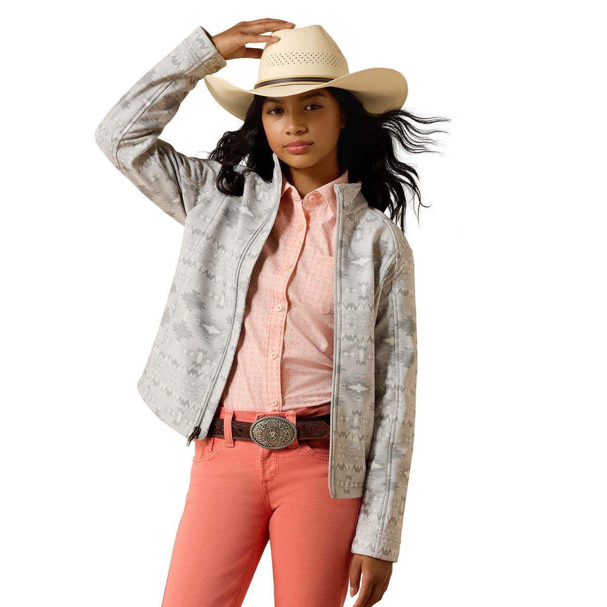A young girl modeling a light gray western-style jacket with a subtle pattern, paired with a pink button-down shirt, coral pants, a brown belt, and a beige cowboy hat against a white background.