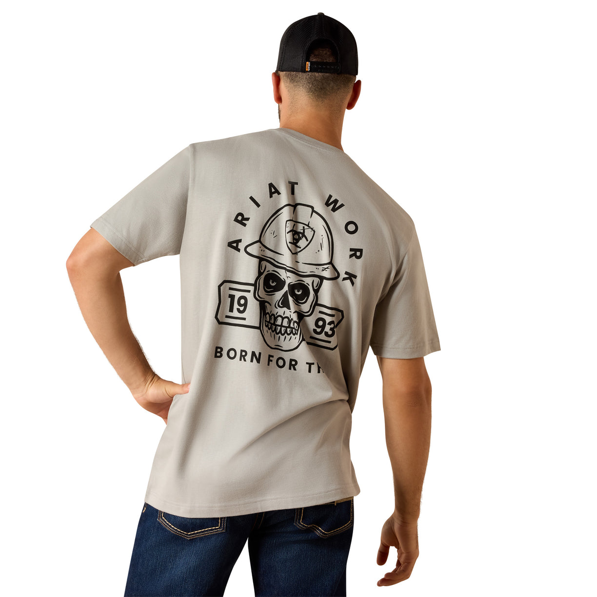 Tan graphic t-shirt with a skull and hard hat print across the back, paired with denim jeans