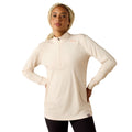 Woman wearing a cream quarter-zip long sleeve top with black leggings