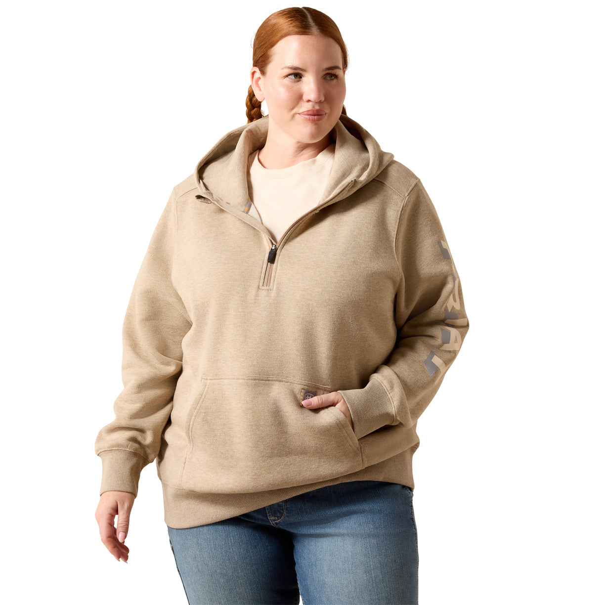 A woman modeling a beige half-zip hoodie with a drawstring hood and kangaroo pocket, paired with blue jeans, against a plain white background.