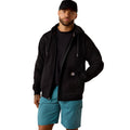 Man wearing a black jacket and blue shorts on a white background