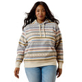 A woman modeling a striped pullover hoodie with a multicolor pattern of beige, blue, yellow, and brown horizontal stripes, paired with light blue jeans against a plain white background.