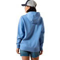 A woman shown from the back wearing a light blue heathered pullover hoodie, denim shorts, and a gray and navy trucker cap against a plain white background.
