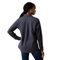 A woman shown from the back wearing a dark slate blue long-sleeve button-up shirt and blue jeans against a plain white background.