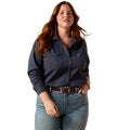 A woman modeling a dark navy long-sleeve button-up shirt with a subtle textured pattern, paired with blue jeans and a brown belt, against a solid white background.