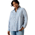 A woman modeling a light blue and white patterned button-down shirt with light-wash jeans against a plain white background.