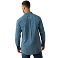 A man viewed from the back wearing a blue long-sleeve button-up shirt with a small white geometric pattern, paired with dark blue jeans against a plain white background.