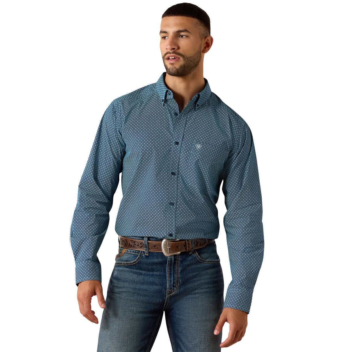 A man wearing a blue long-sleeve button-down shirt with a small white geometric pattern, paired with blue jeans and a brown belt, against a plain white background.
