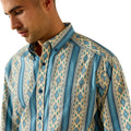 A man wearing a long-sleeve button-down shirt with vertical stripes and diamond geometric patterns in shades of blue, teal, and beige.