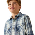 A smiling young man wearing a blue and white plaid western-style button-down shirt with two chest pockets and a small embroidered logo on the pocket, photographed against a clean white background.