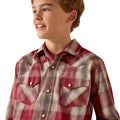 A young boy wearing a red and beige plaid western-style button-down shirt, shown from the chest up against a plain white background.