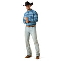A man modeling a blue and white patterned long-sleeve western shirt, paired with light blue jeans, a brown belt, brown boots, and a black cowboy hat, against a plain white background.