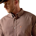 A man wearing a brown and white checkered button-down shirt with a small embroidered logo on the chest, paired with a black cowboy hat against a white background.