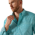 Man wearing a teal patterned shirt against a white background