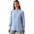 Woman wearing a light blue striped blouse with ruffled details on a white background