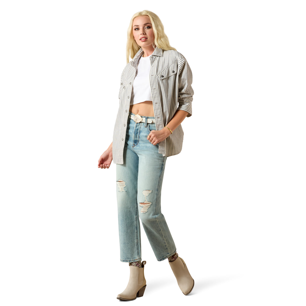 Woman wearing a striped shirt, white crop top, and light blue jeans on a white background