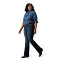 Woman wearing a blue patterned blouse and jeans on a white background