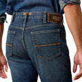 Person wearing blue jeans with Ariat branding on a white background