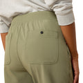 Person wearing olive green pants with a pocket detail on a plain background