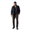 Man wearing a blue beanie, black vest, blue shirt, gray pants, and black shoes on a white background
