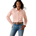 A woman modeling a light pink long-sleeve western-style button-up shirt with a subtle grid pattern, tucked into blue jeans with a brown patterned belt, against a solid white background.