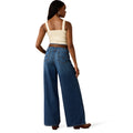 Woman wearing blue jeans and a beige top on a white background