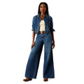 Woman wearing a denim jacket and wide-leg jeans on a white background