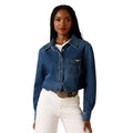 Woman wearing a blue denim jacket and white pants on a white background