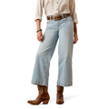 Model wearing light blue crop Ariat jeans and brown cowboy boots.