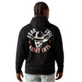 A man viewed from the back wearing a black hoodie with a large graphic on the back. The graphic features a cowboy hat and skull in white, with the words 'FEAR EVIL' in white and 'Ariat Intl' in red-pink.