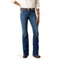 A model wearing a pair of medium-wash blue jeans with a white button-down shirt, a dark brown belt, and brown leather shoes, shown from the waist down on a white background.