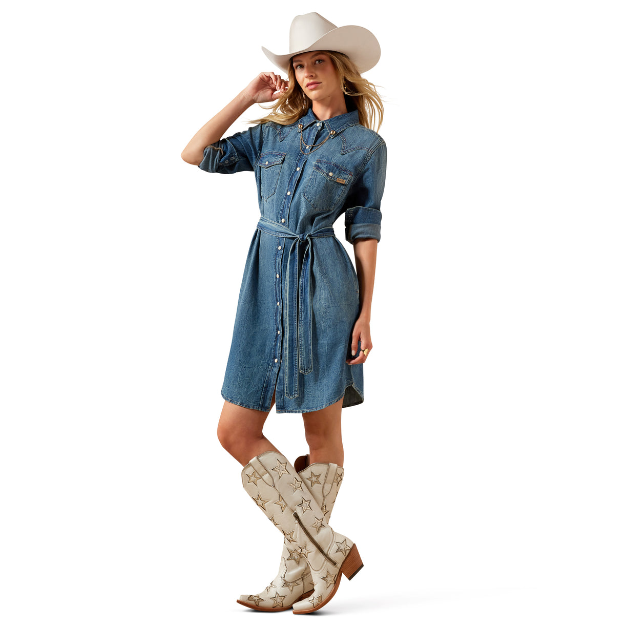 Woman wearing a denim dress, white cowboy hat, and white cowboy boots on a white background