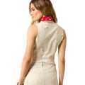 Woman wearing a beige sleeveless top with star designs on a white background