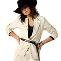 Woman wearing a white jacket with black trim, black hat, and black belt on a white background
