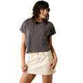 Woman wearing a dark gray t-shirt with star patterns and a white skirt on a white background
