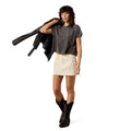 Woman wearing a dark gray t-shirt with star patterns, white shorts, and black boots on a white background