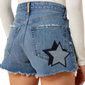 Blue denim shorts with a star patch on a white background