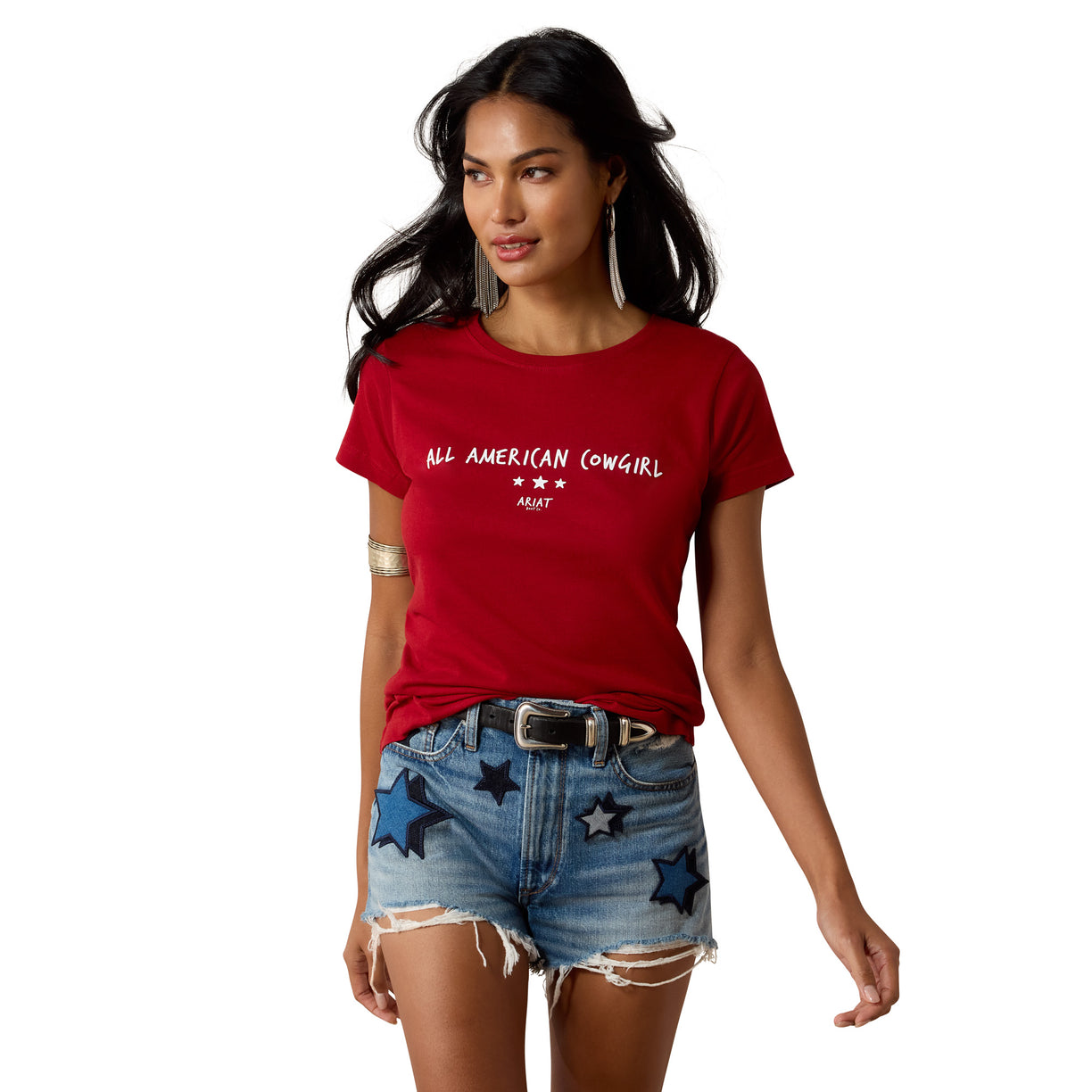Woman wearing a red t-shirt with 'All American Cowgirl' text and denim shorts with star designs on a white background