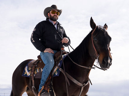 Cowboy riding a horse in the snow wearing Ariat Acclimatize denim jeans