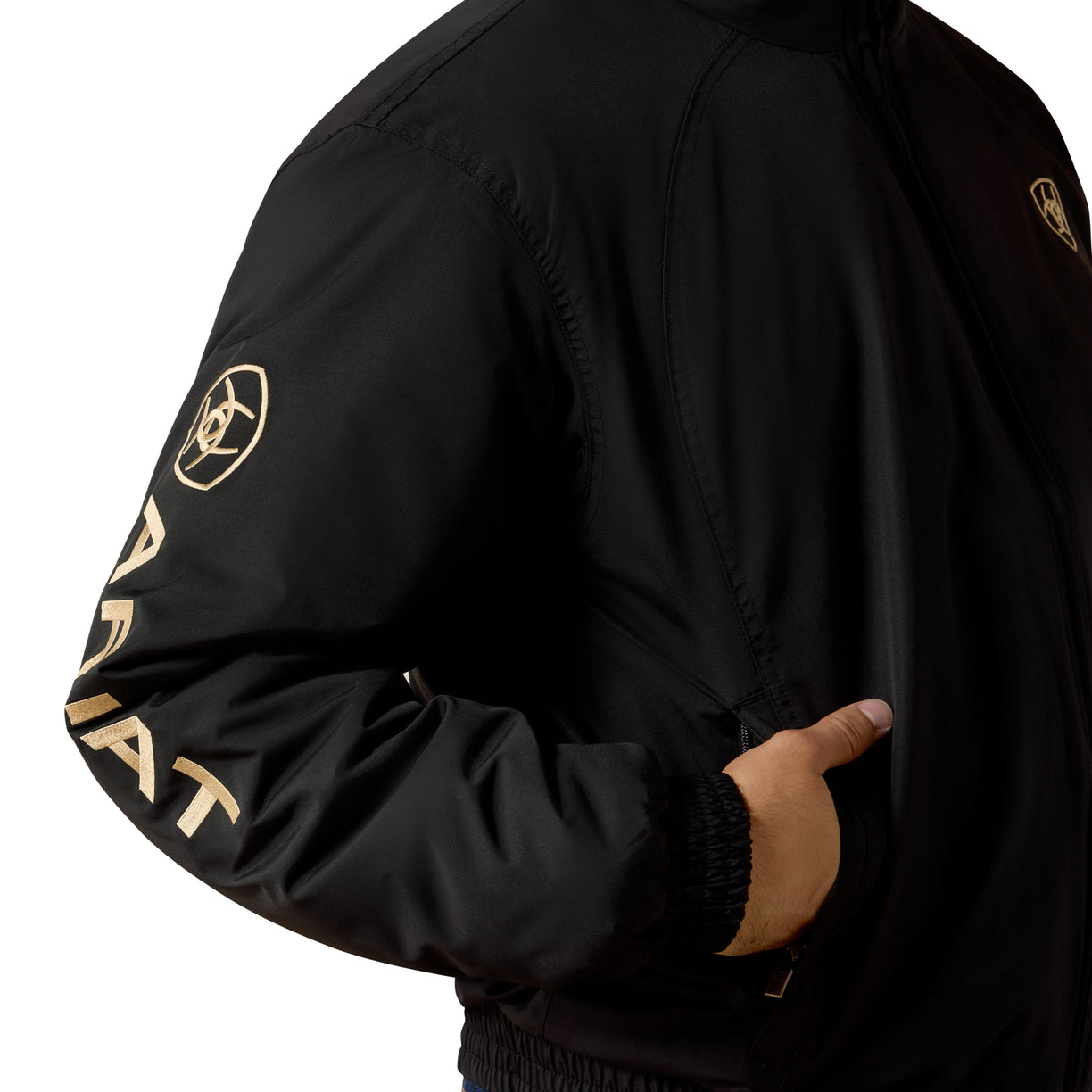 Black jacket with gold text and logo on sleeve, worn by a person.