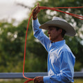 Man in a cowboy hat holding a red lasso with a blurred green background
