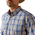 Man wearing a blue and brown plaid shirt with a visible brand logo.