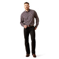 Man wearing a patterned shirt and black pants on a white background