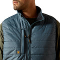 Close-up of a person wearing a blue puffer vest with a brand logo on a white background