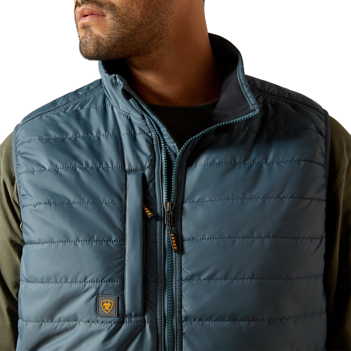 Close-up of a person wearing a blue puffer vest with a brand logo on a white background