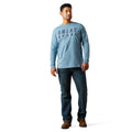 Man wearing a light blue long-sleeve shirt with 'Ariat' branding on a white background
