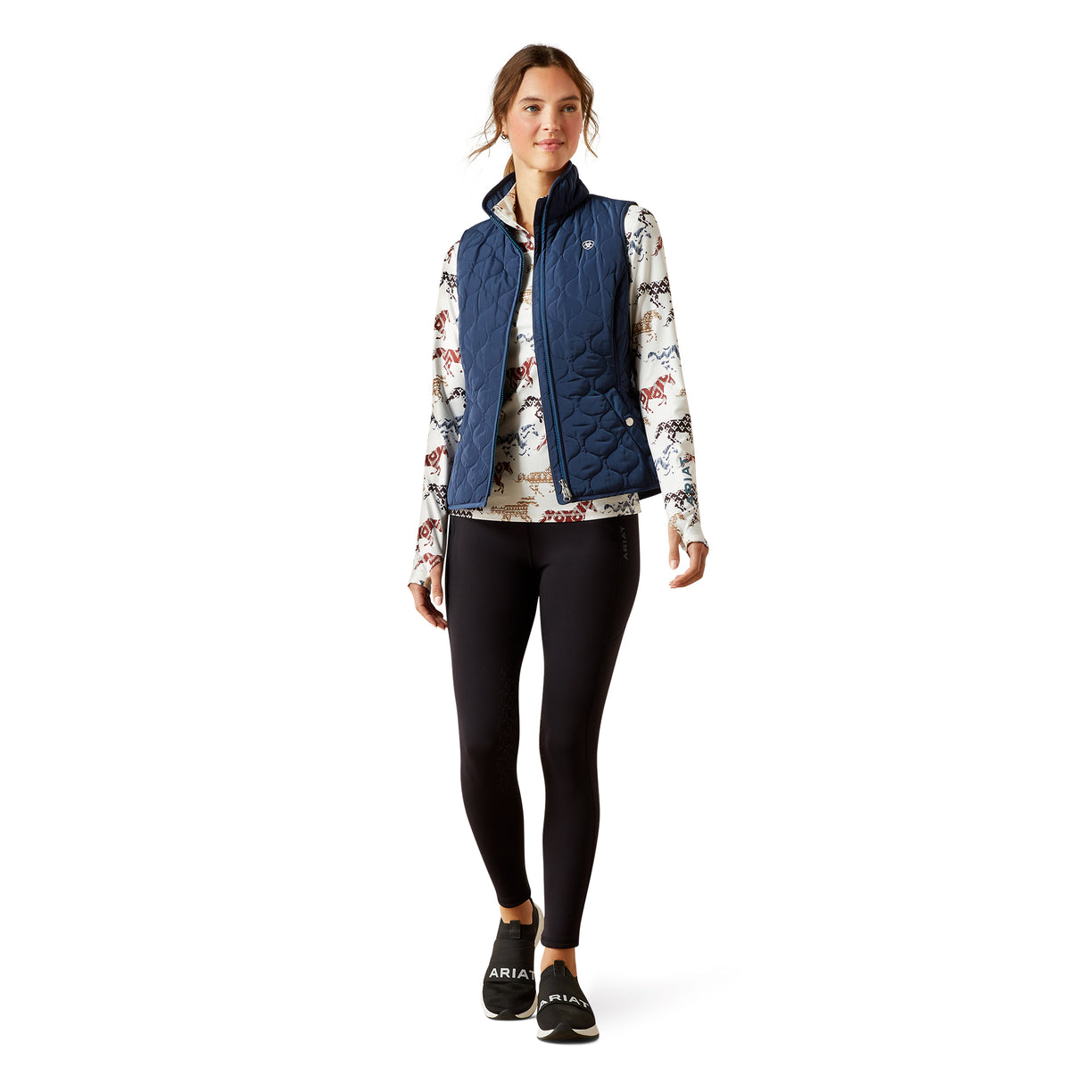 Woman wearing a blue puffer vest over a floral shirt on a white background