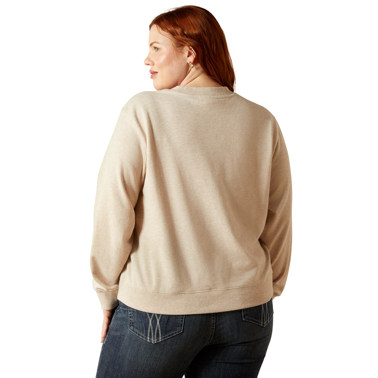 Person wearing a beige sweatshirt and dark jeans on a white background